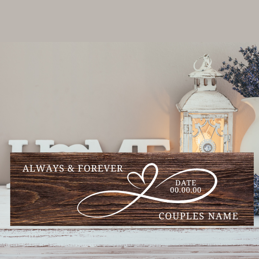 Wooden sign with "Always & Forever" and space for a date and couple's name, placed on a surface with a decorative lantern in the background.