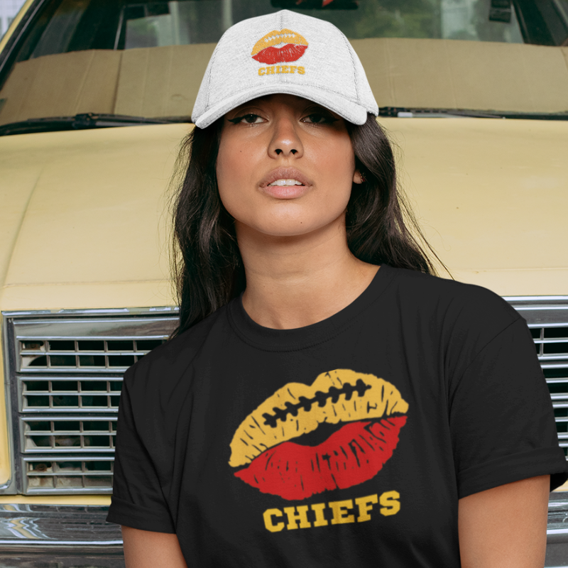 A woman wearing game day t-shirt in black color with a lip-themed design in yellow gold and red on top and the team name written below. 