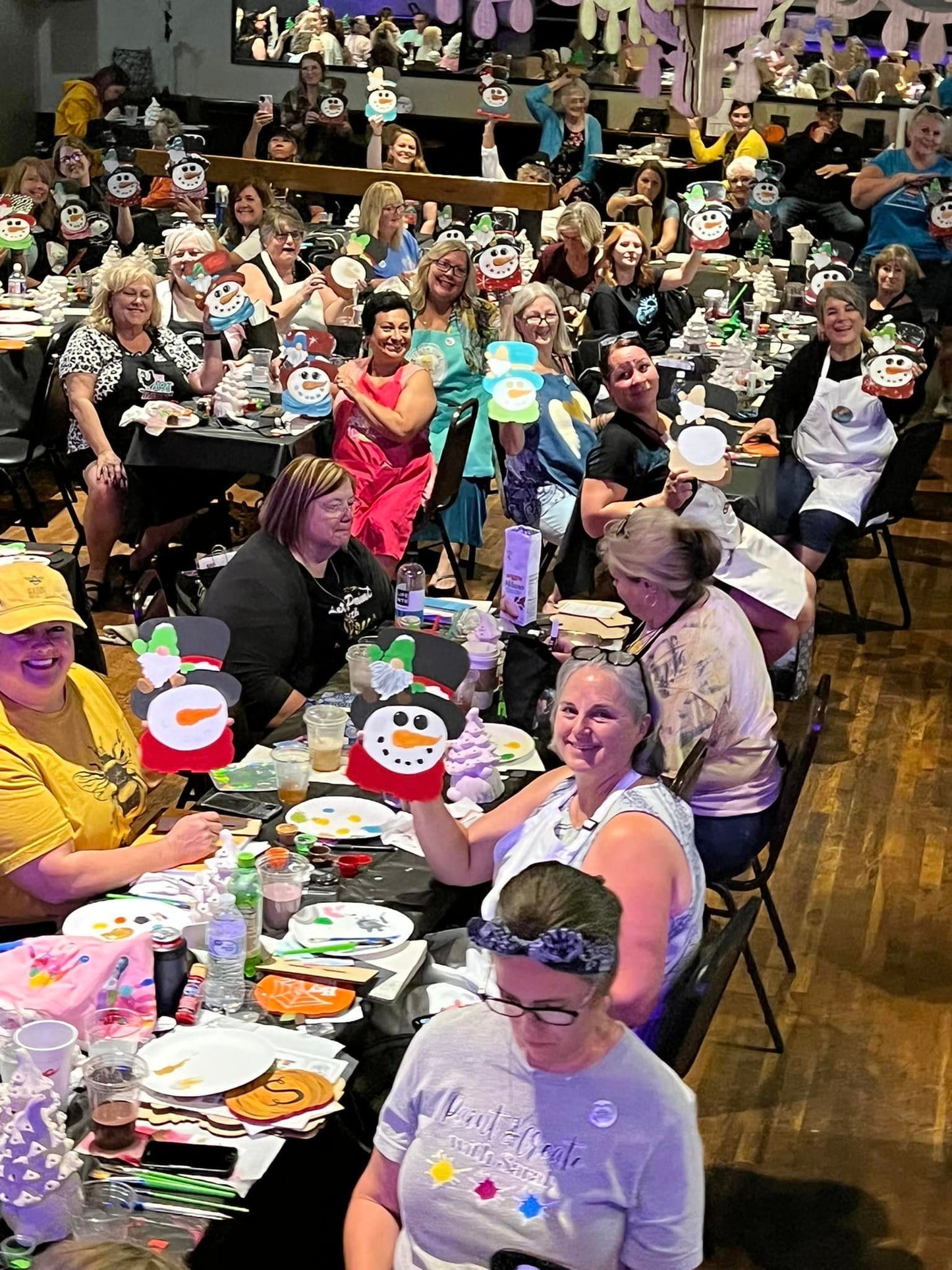 Group of women having a blast a t a Christmas themed paint party of a snowman
