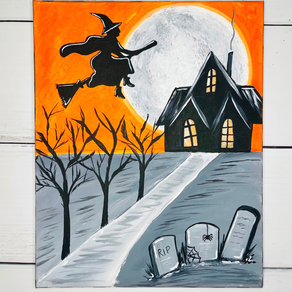 The Witch Is In Witches of Halloween DIY paint kit, witch on a broom over a haunted house, full moon, and tombstones on an orange sky