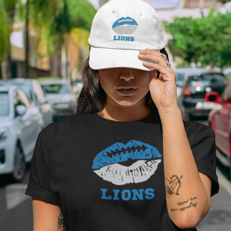 A woman wearing game day t-shirt in black color with a lip-themed design in blue and white on top and the team name written below. 