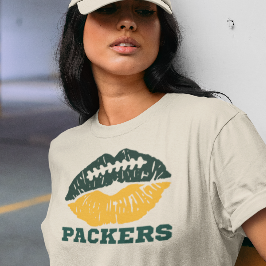 A woman wearing a cream t-shirt with a lip-themed football design reading Packers