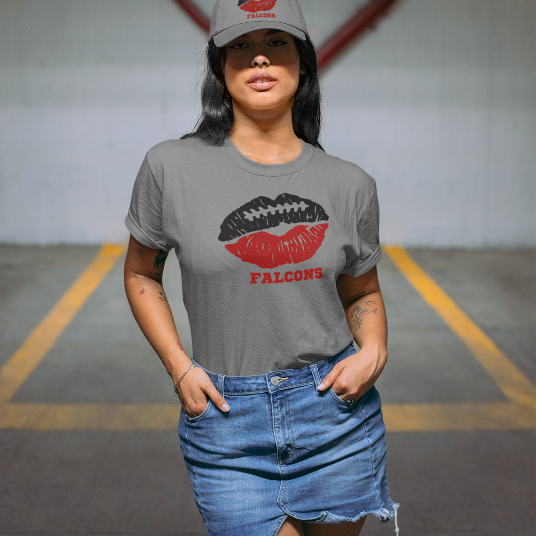 A woman wearing a gray t-shirt with a red and black lips football graphic and the word FALCONS underneath