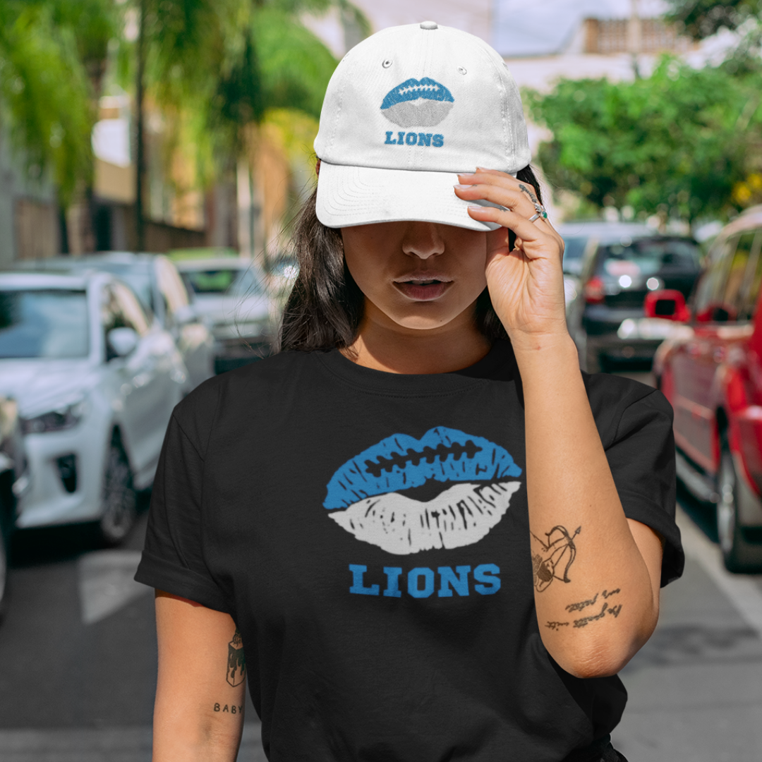 A woman wearing football game day t-shirt in black color with a lip-themed design in blue and silver on top and the team name Lions