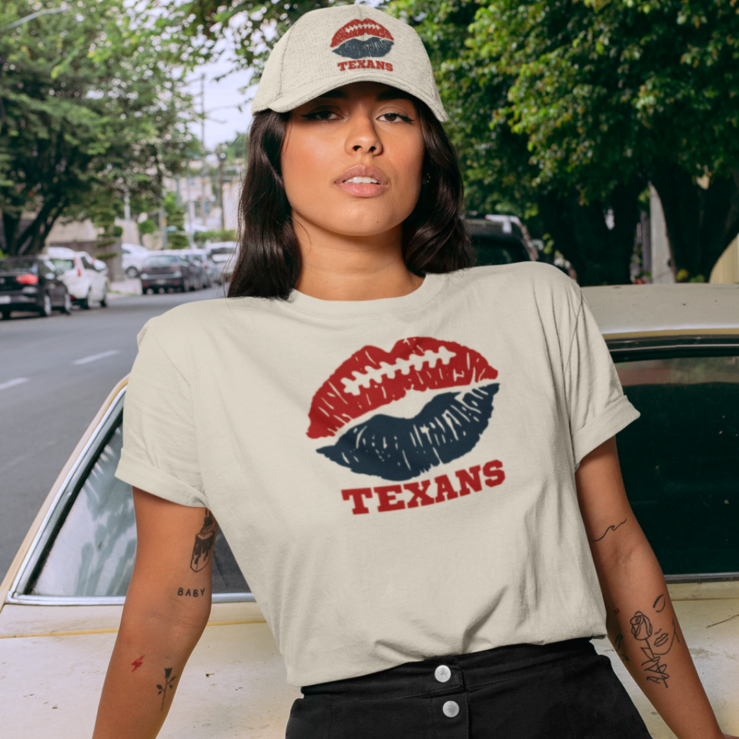A woman wearing football game day t-shirt in cream color with a lip-themed design in red and deep blue on top and the team name Texans written below.